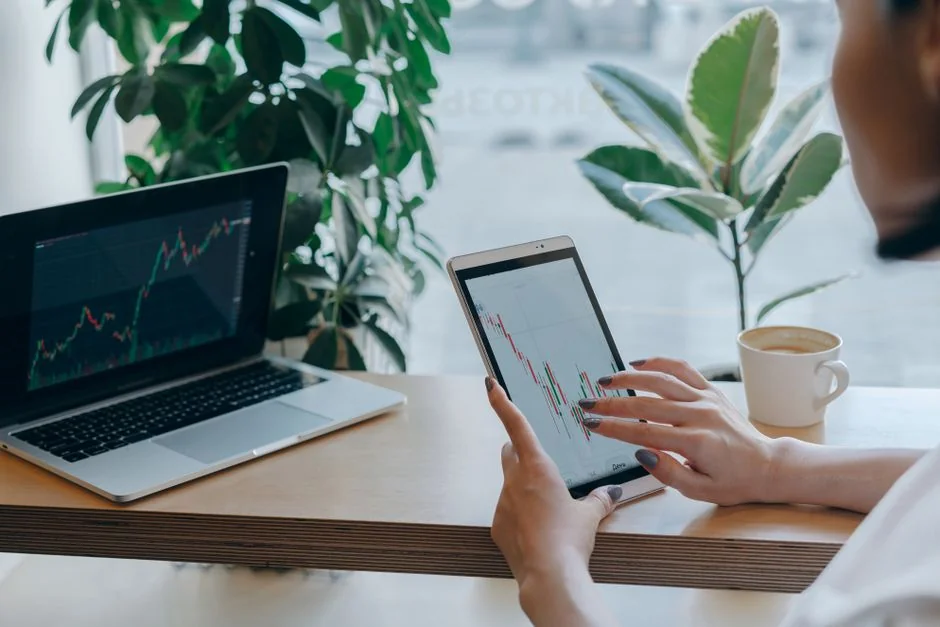 A contemporary workspace where hands review marketing data on a laptop alongside paper documents.